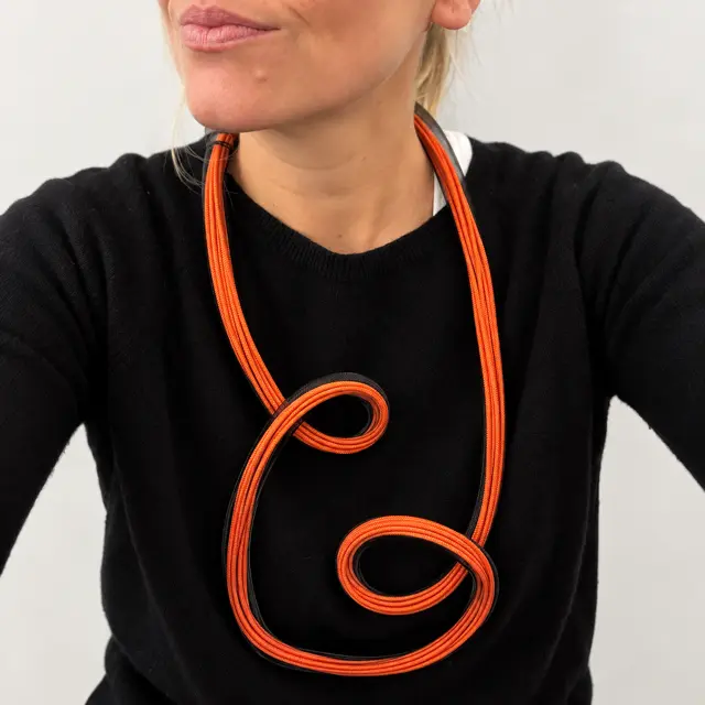collana scultorea arancione e nera con rete metallica ed elastici indossata